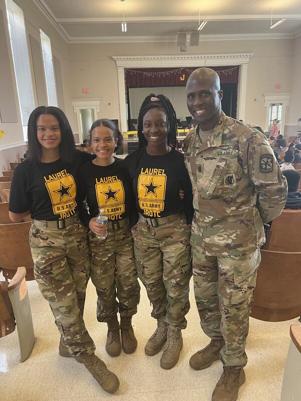 Students standing posing for a picture with their JROTC Instructor in army uniform.