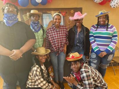 Students posing for picture wear cowboy clothes.