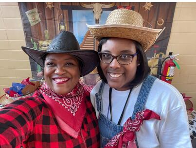 Two ladies posing for picture in cowboy clothes.
