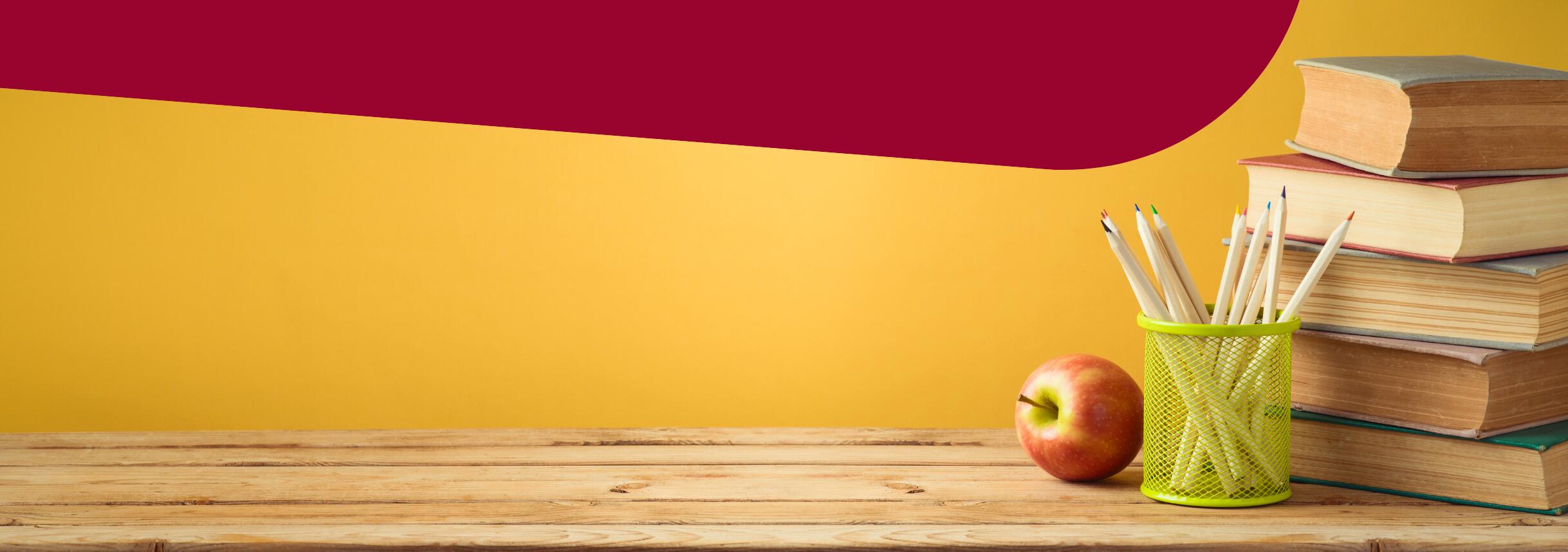 Yellow and Maroon background with school books, pencils and an apple on a wood table.