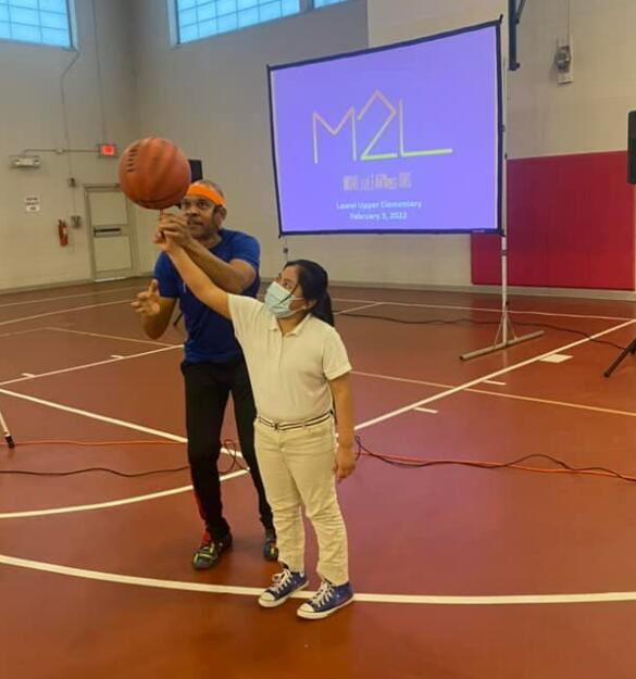 Young girl learning how to spin a basketball with instructor